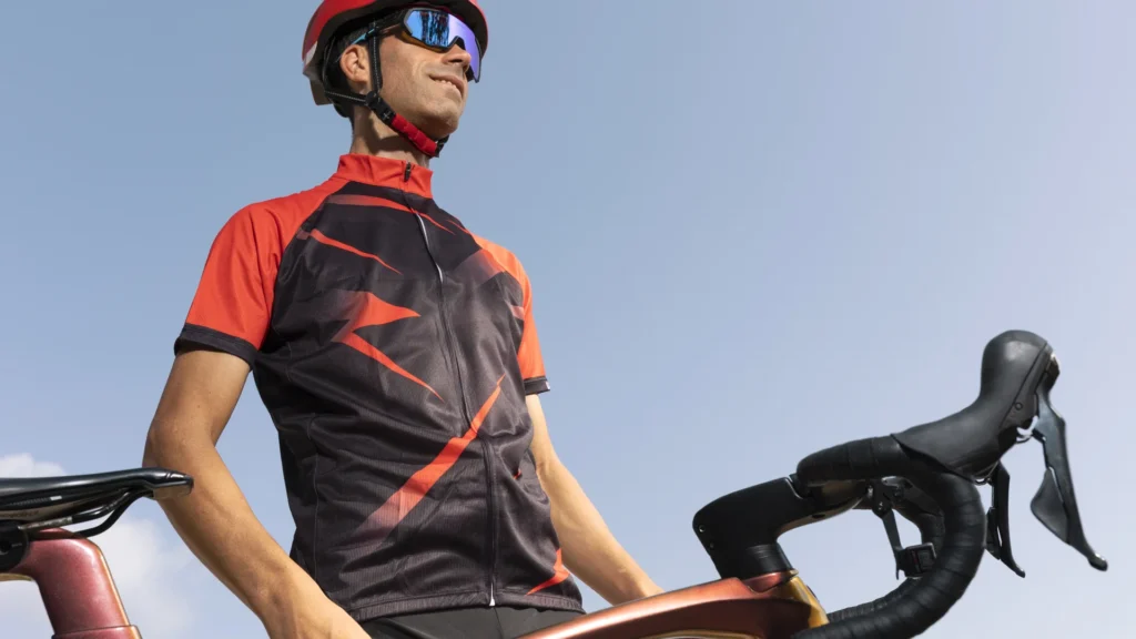 Ciclista con maillot personalizado de ajuste race fit apoyado en su bicicleta