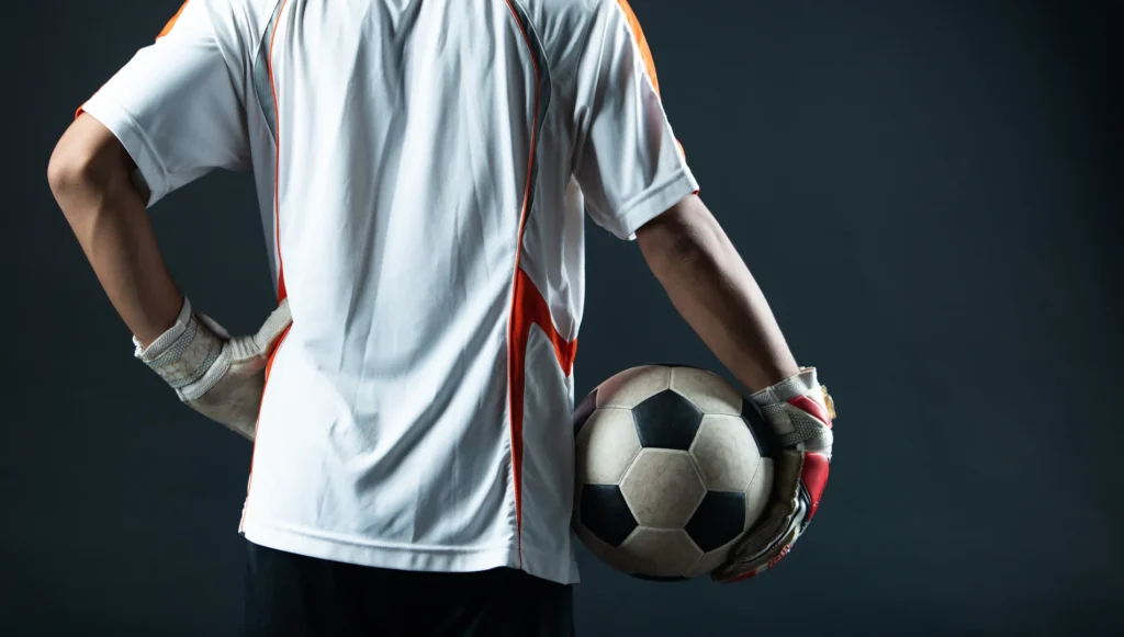 Ropa de portero con guantes y balón, parte de la equipación deportiva para clubes de fútbol base