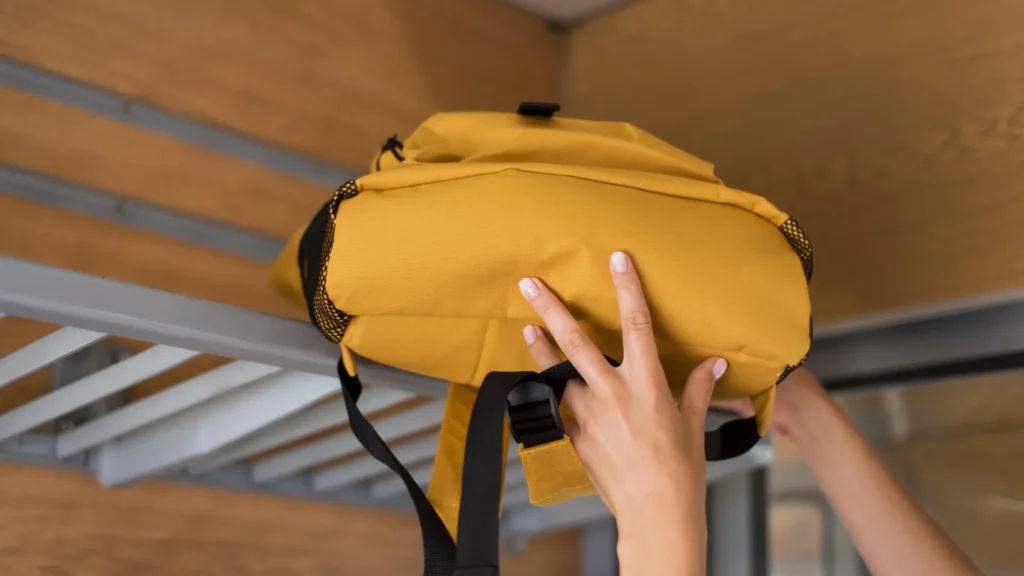 Mochila amarilla de merchandising deportivo personalizado colocada en la rejilla portaequipajes.
